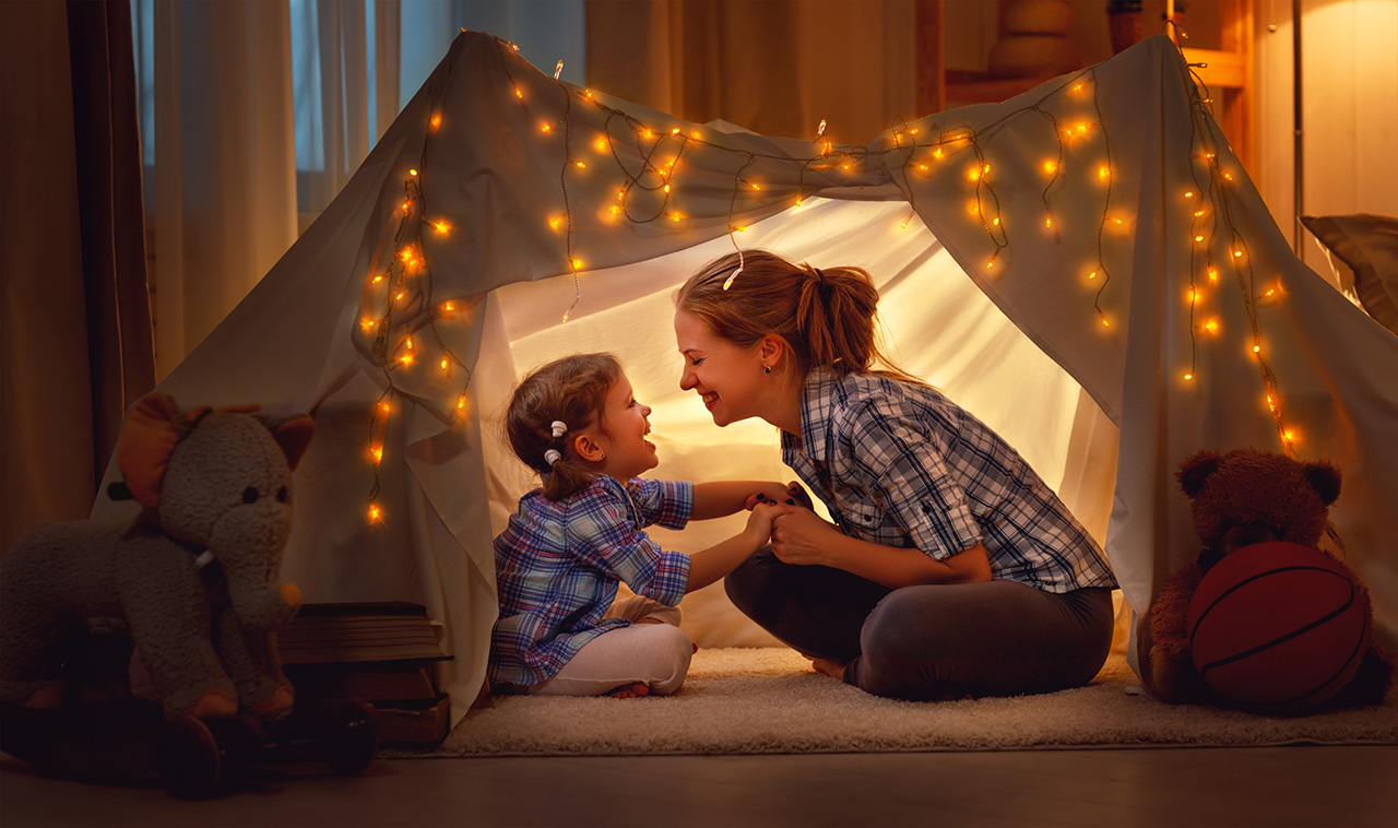 happy mother and daughter playing at home in tent.